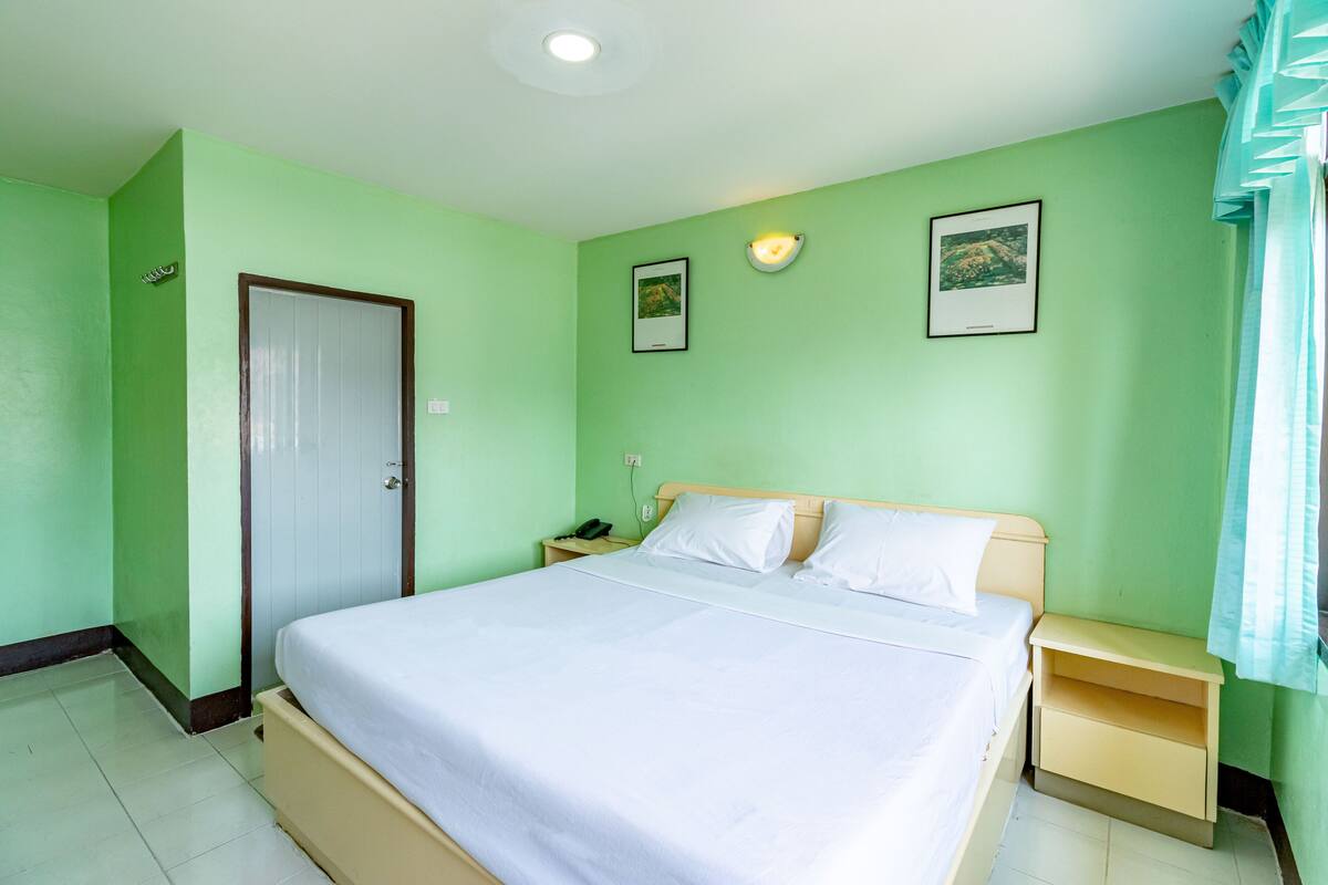 A neatly arranged bedroom with a bed, bedside tables, a wardrobe, and a door.