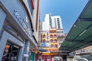 A building with a sign for "Rooms for Rent Indian Restaurant" and a modern building in the background. - Woodlands Inn (Bangkok)