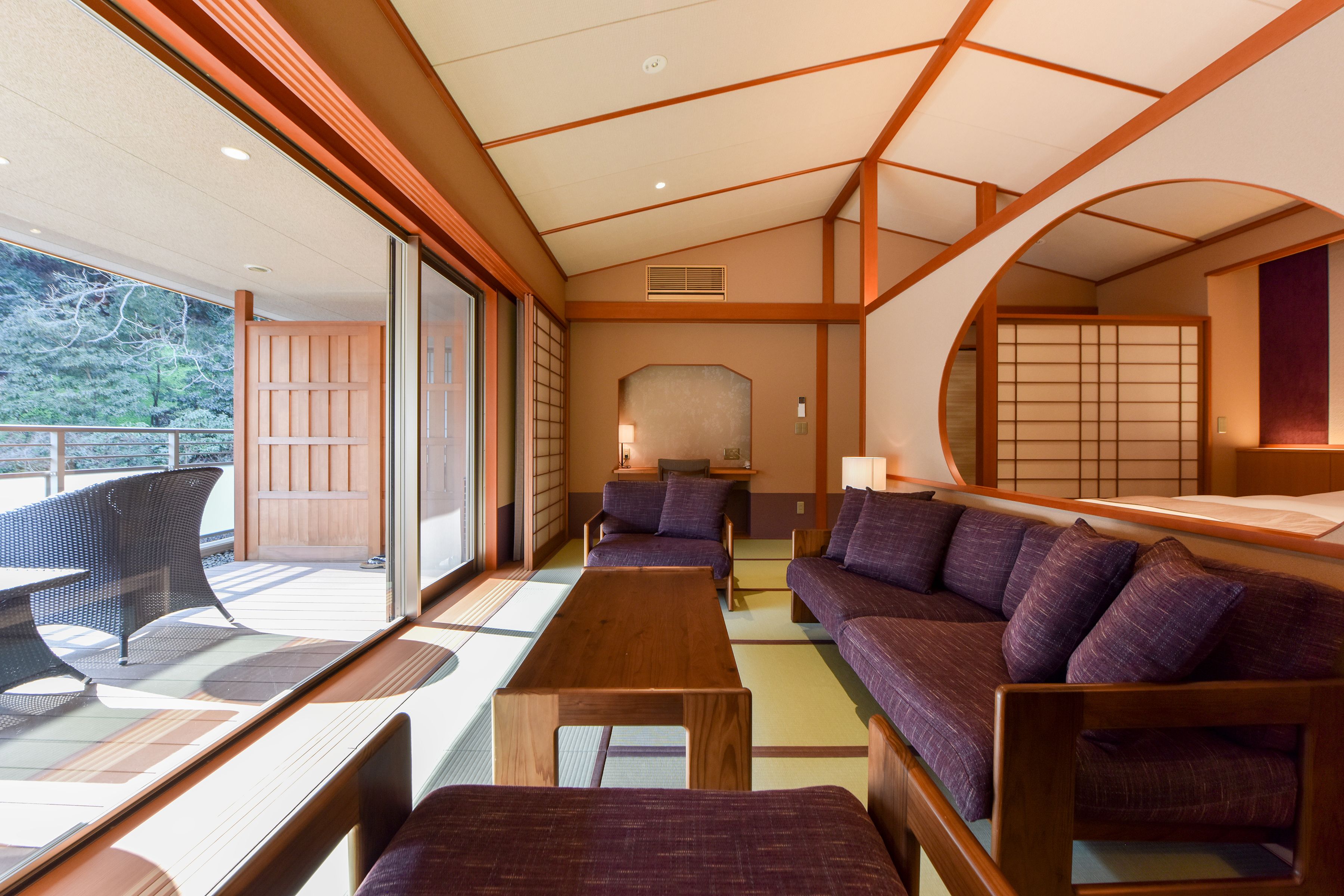 A traditional Japanese-style room with tatami flooring, low wooden tables, and purple cushions.