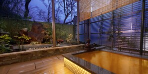 Un espace extérieur moderne agrémenté d’un mur en pierre, d’une terrasse en bois et d’un élément décoratif aquatique.