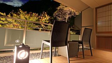 A balcony with two wicker chairs, a small table, and a decorative light fixture.