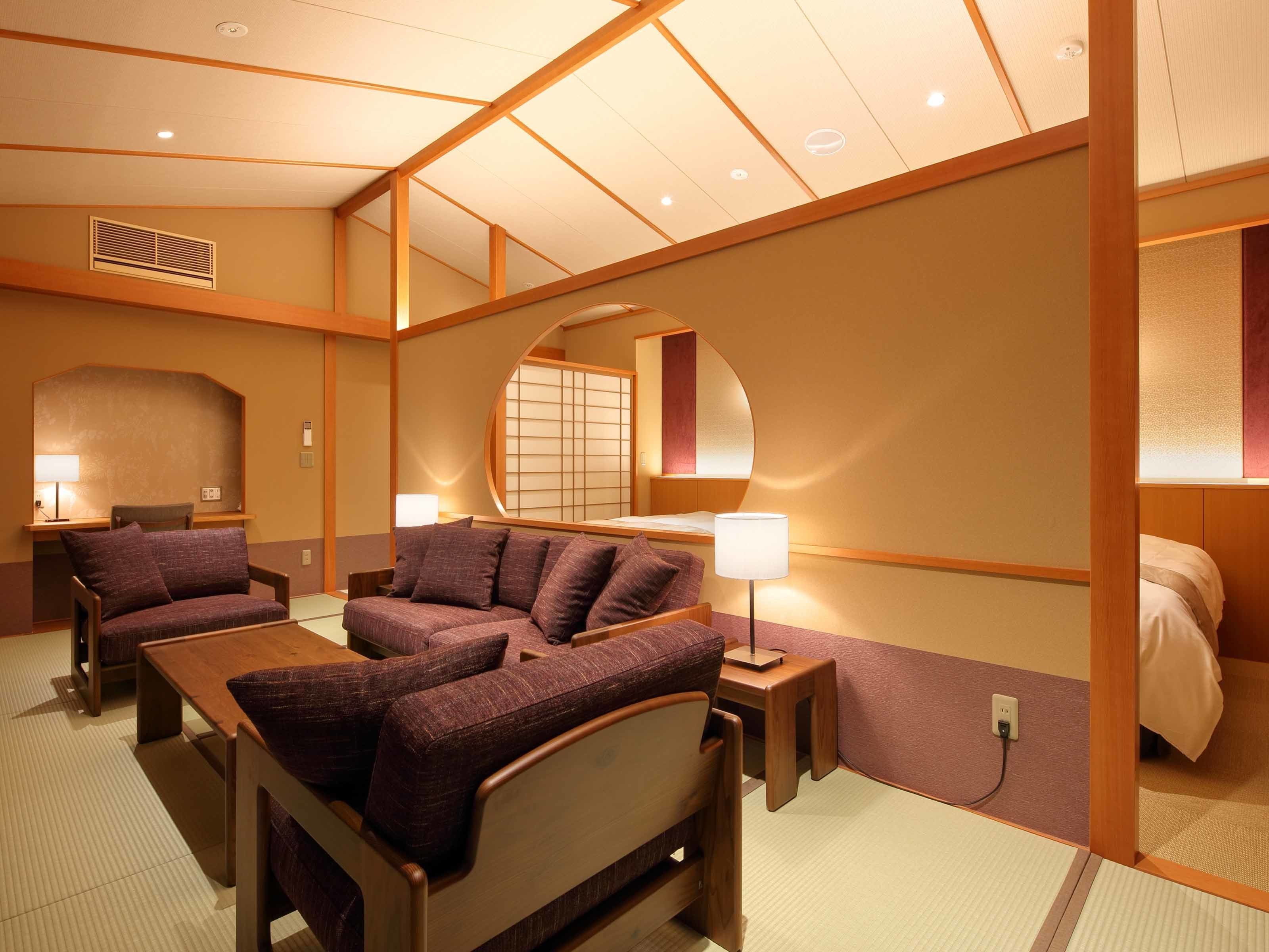 A hotel room with a sofa, a bed, a desk, and a mirror.
