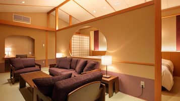 A hotel room with a sofa, a bed, a desk, and a mirror.