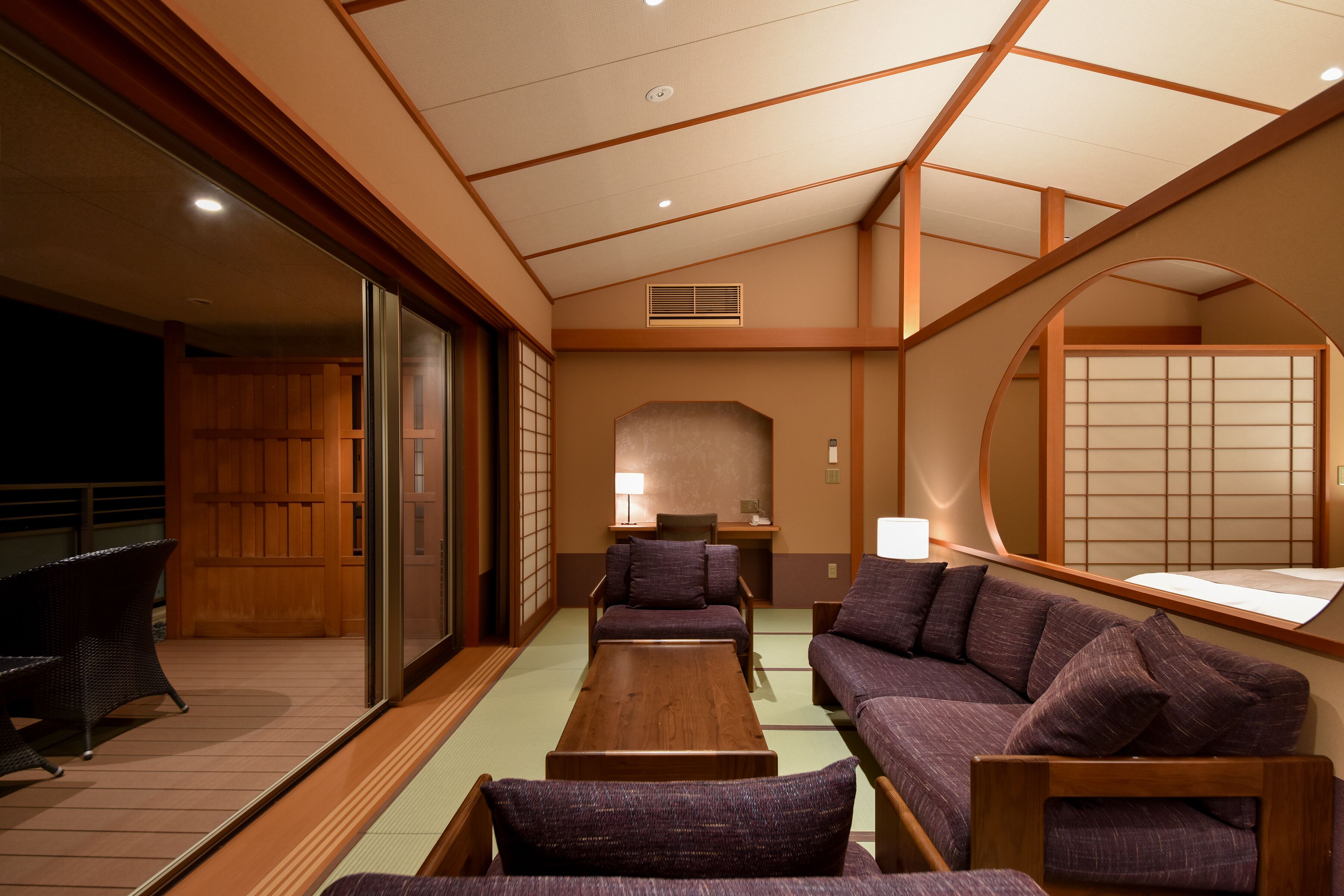 A traditional Japanese-style room with tatami flooring, low wooden tables, and purple upholstered seating.