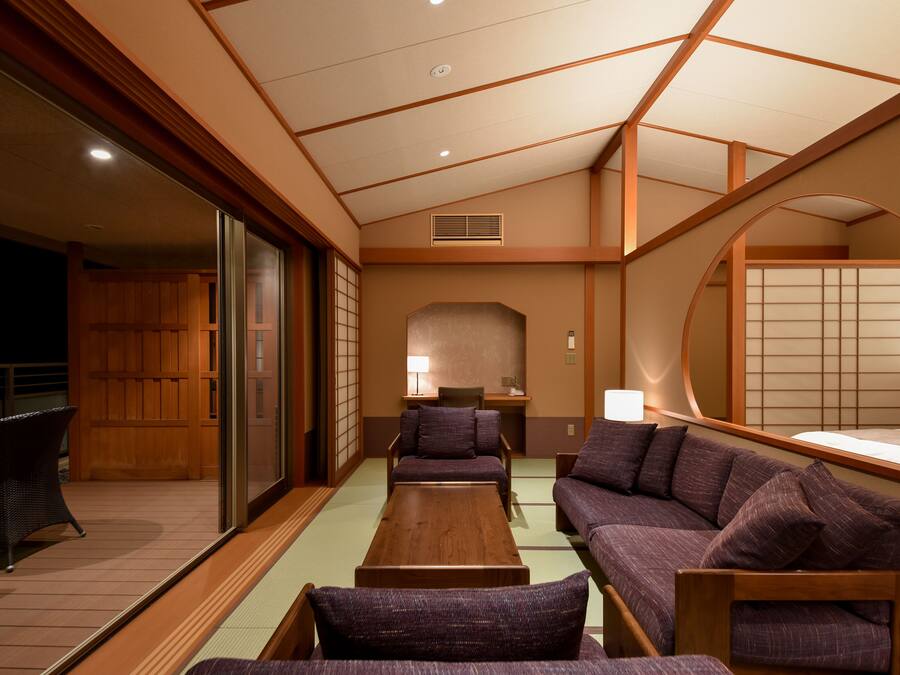 A traditional Japanese-style room with tatami flooring, low wooden tables, and purple upholstered seating.