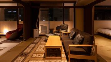 A modern living room with a sofa, chairs, a coffee table, and a bed.