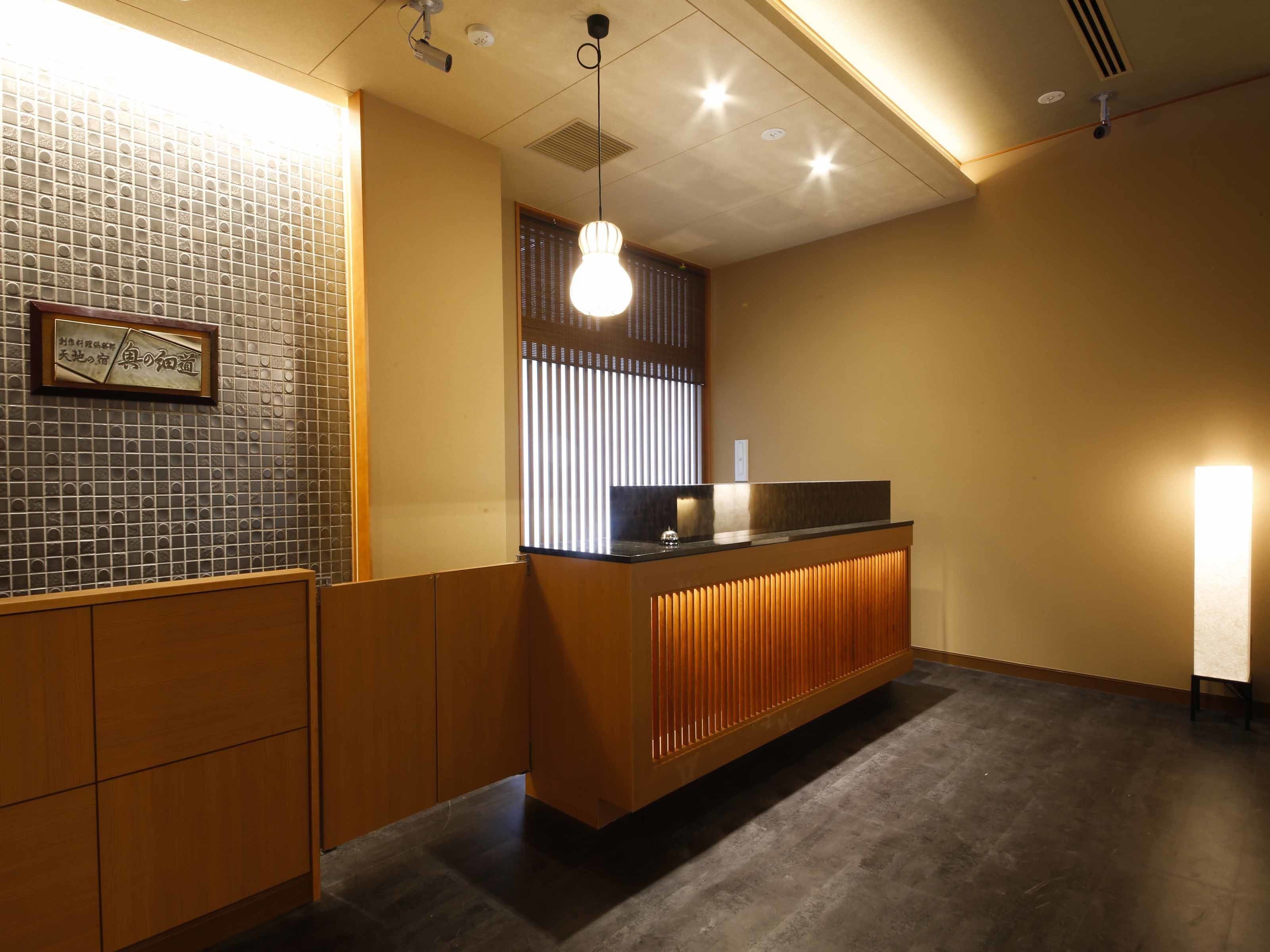 A reception area with a wooden counter, a tiled wall, and a ceiling with recessed lighting.