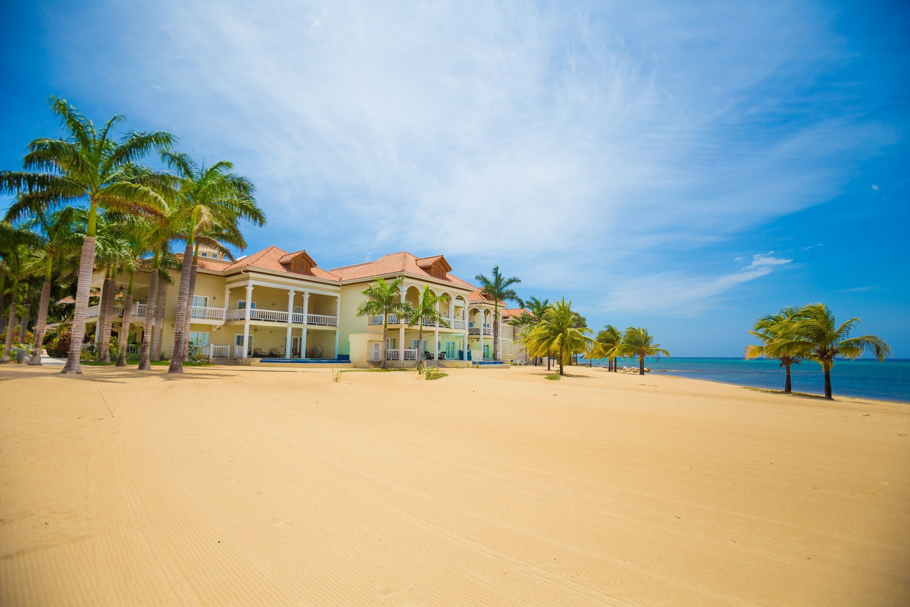 A beachfront hotel with multiple balconies and palm trees.