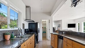Een moderne keuken met granieten aanrechtbladen, roestvrijstalen apparatuur en houten keukenkastjes.