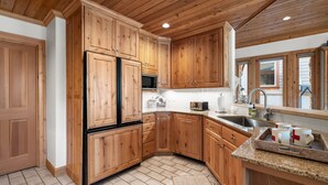 Una cucina con mobili in legno, un frigorifero, un forno a microonde, un lavello e una finestra.