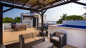 Eine Terrasse im Freien mit Korbmöbeln, einem Grill und einem Swimmingpool.