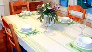 Ein Esstisch mit Tellern, Gläsern und einer Blumenvase.