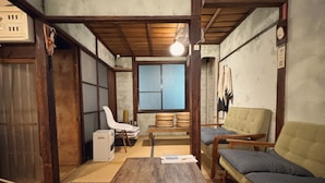 A traditional Japanese room with tatami flooring, a wooden table, a sofa, and a futon. - Hostel Otro Mundo (Kyoto)