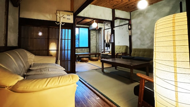 A traditional Japanese-style room with tatami flooring, a low wooden ceiling, and a futon bed. - Hostel Otro Mundo (Kyoto)