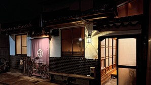 A hostel with a tiled exterior, a bicycle parked outside, and a sign indicating it is a hostel. - Hostel Otro Mundo (Kyoto)