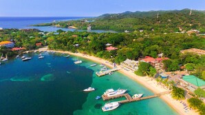 Une vue aérienne d’une zone côtière avec une plage, des bateaux et des bâtiments.
