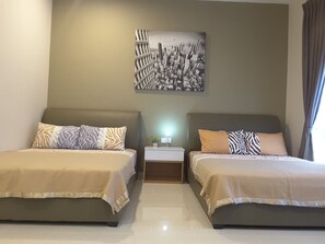 A hotel room with two beds, a nightstand with a lamp, and a wall-mounted picture.