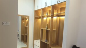 A walk-in closet with wooden shelving and a mirrored closet door. - Laman Kurnia Holiday House (Kota Bharu)