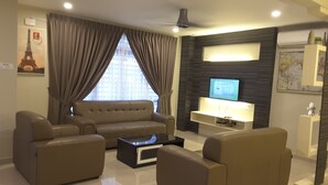 A modern living room with a sofa, two armchairs, a coffee table, and a flat-screen TV. - Laman Kurnia Holiday House (Kota Bharu)