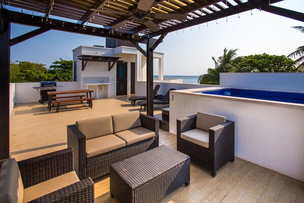 An outdoor patio with wicker furniture, a barbecue, and a swimming pool.