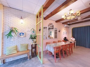 A cozy room with a brick wall, a wooden bench, a dining table with chairs, and a chandelier. - Hualien Yashe House (Hualien City)