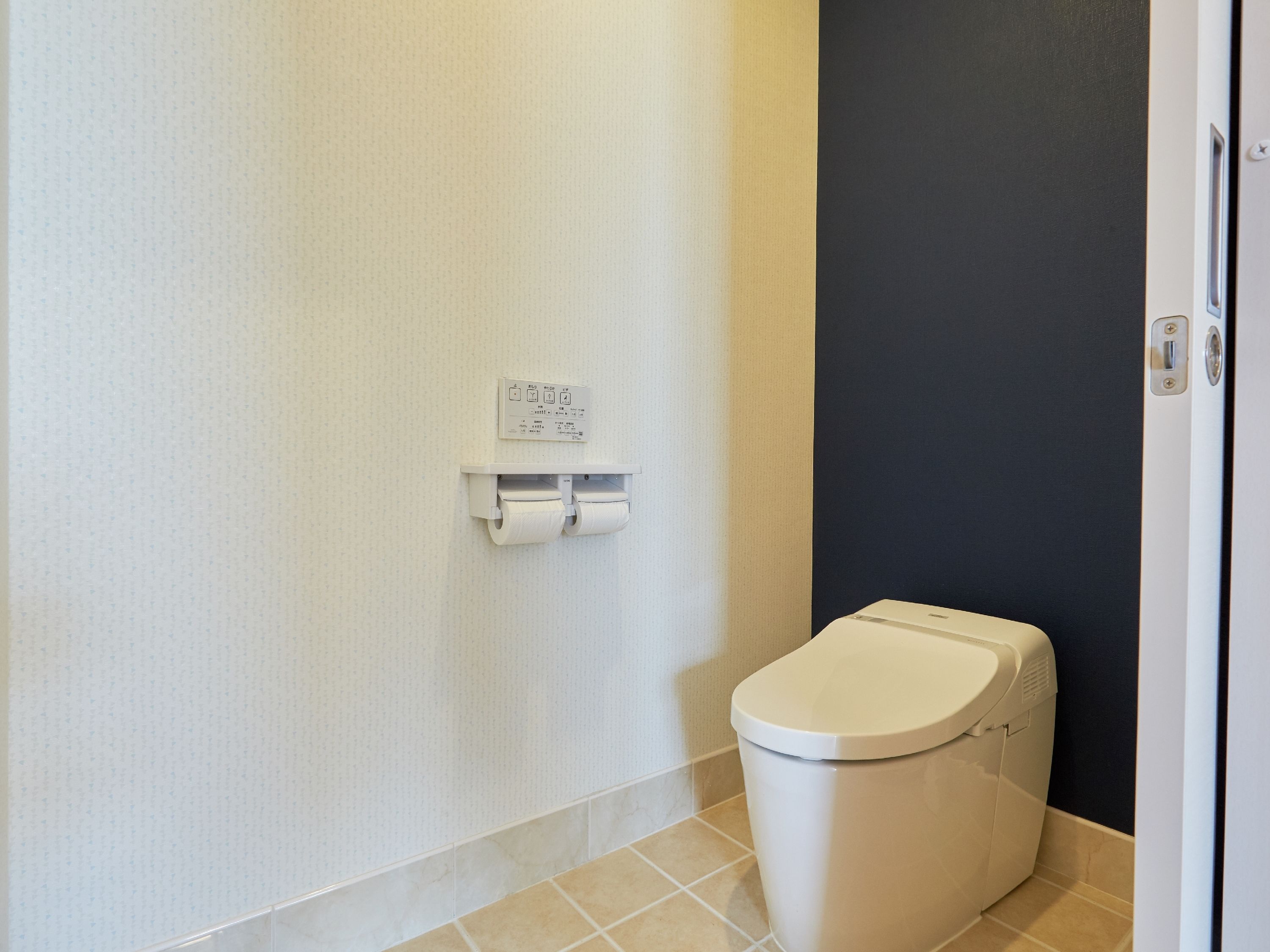 Un baño pequeño con inodoro, dispensador de papel higiénico en la pared y puerta.
