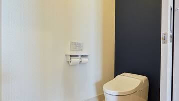 Un baño pequeño con inodoro, dispensador de papel higiénico en la pared y puerta.
