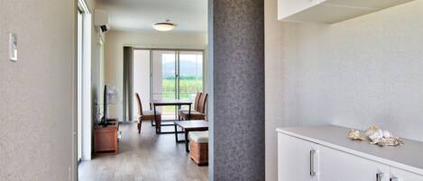 Una cocina moderna con armarios blancos, un comedor con mesa y sillas, y vistas al exterior a través de amplios ventanales correderas.