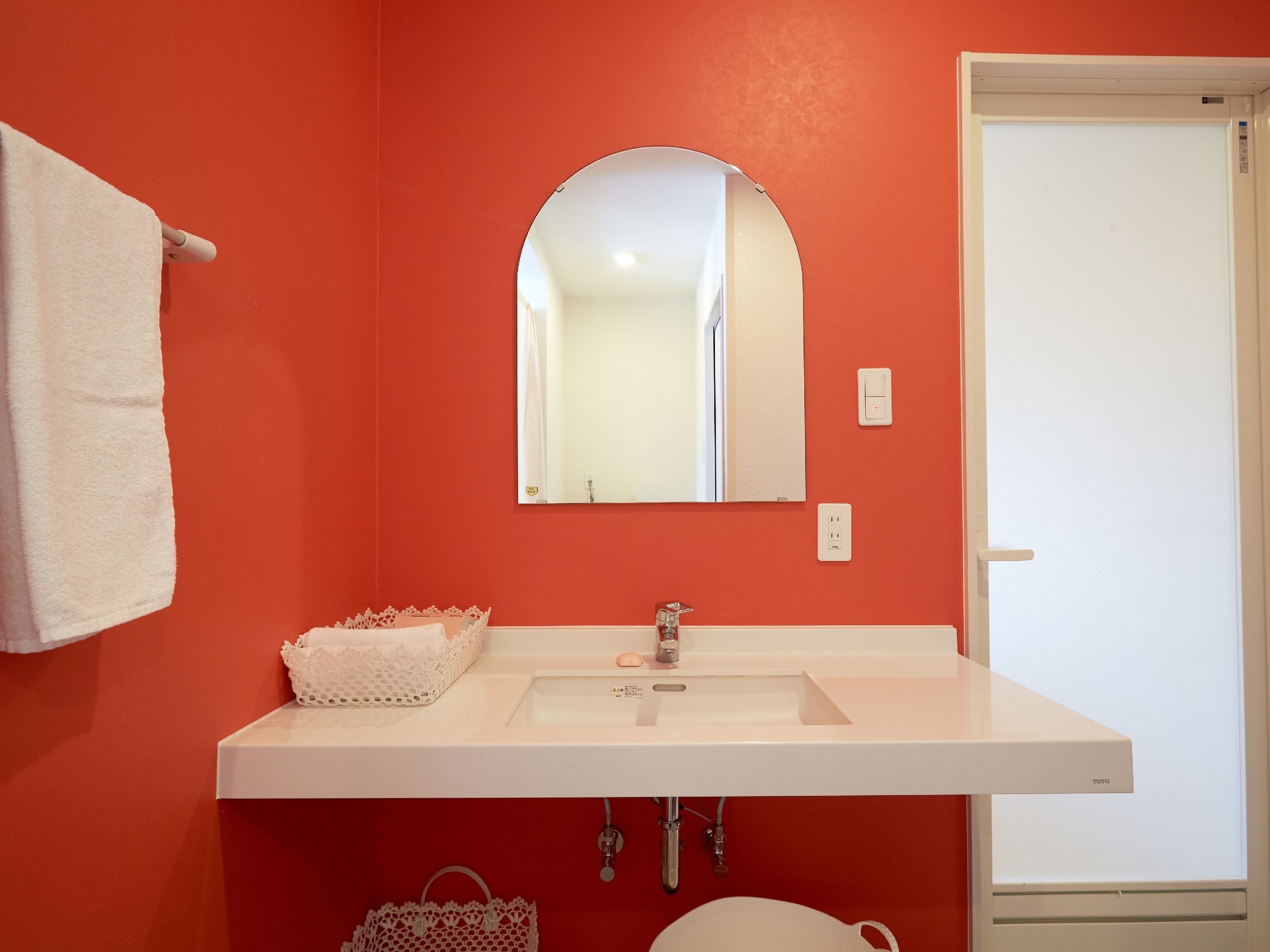 A bathroom with a white sink, a mirror, and a towel hanging on the wall.