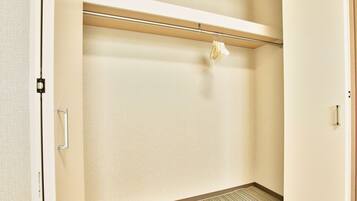 A hotel room with a striped carpet, a hanging rack, and a door with a handle.