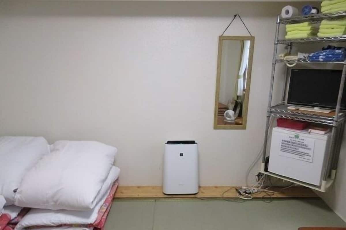 Een hotelkamer met een bed, nachtkastje, spiegel en een plank met toiletartikelen.