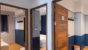 Habitación de hotel con puerta de madera, una cama, un cubo de basura pequeño y una toalla en el suelo.