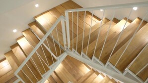 Una escalera de madera con barandas blancas e iluminación empotrada.
