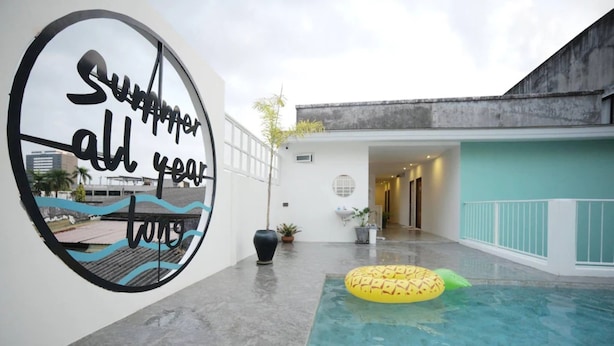 Una piscina interior con un amplio mural en la pared, una piscina inflable pequeña y una planta en maceta.