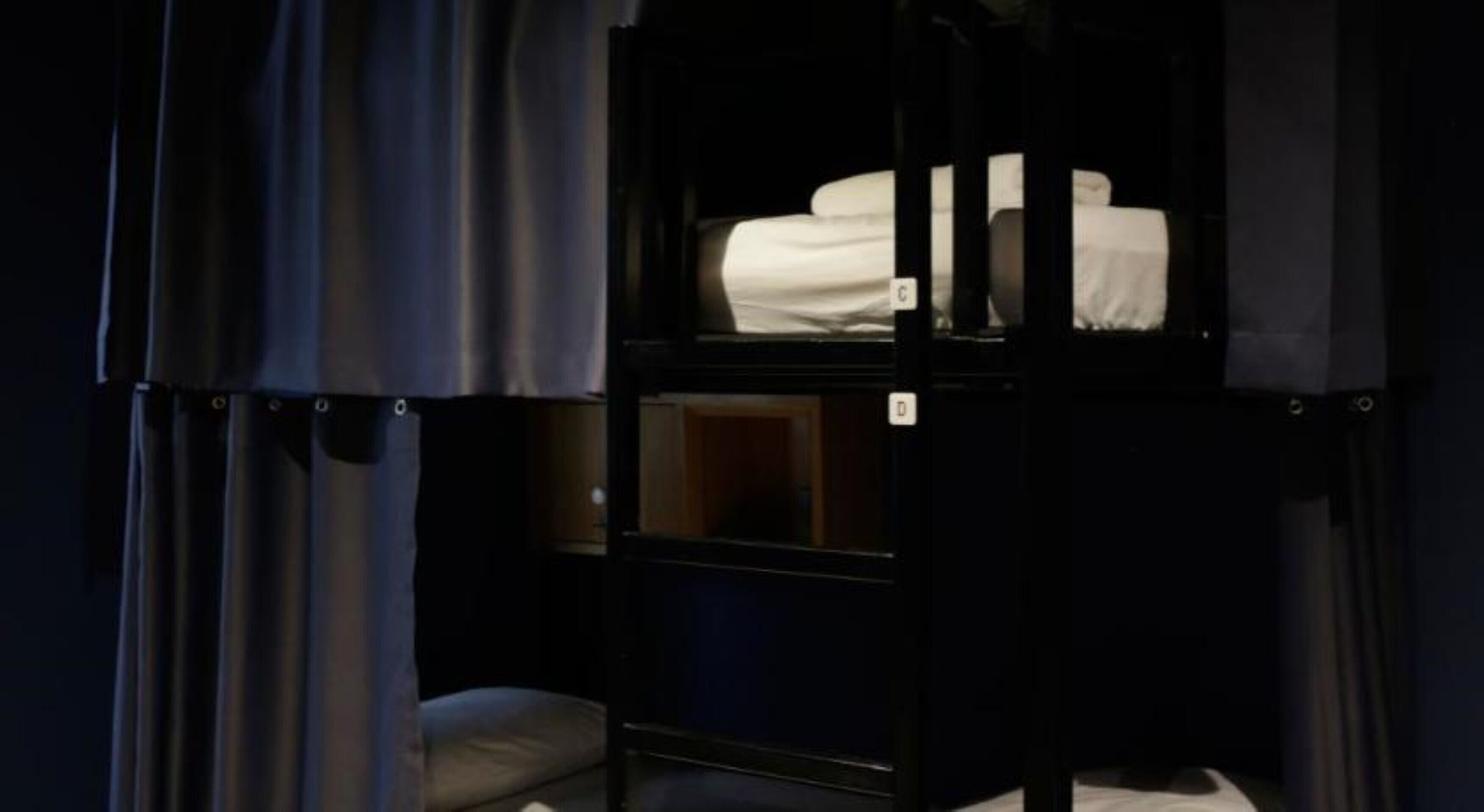 Quarto com beliche, um pequeno armário e janela com cortinas.
