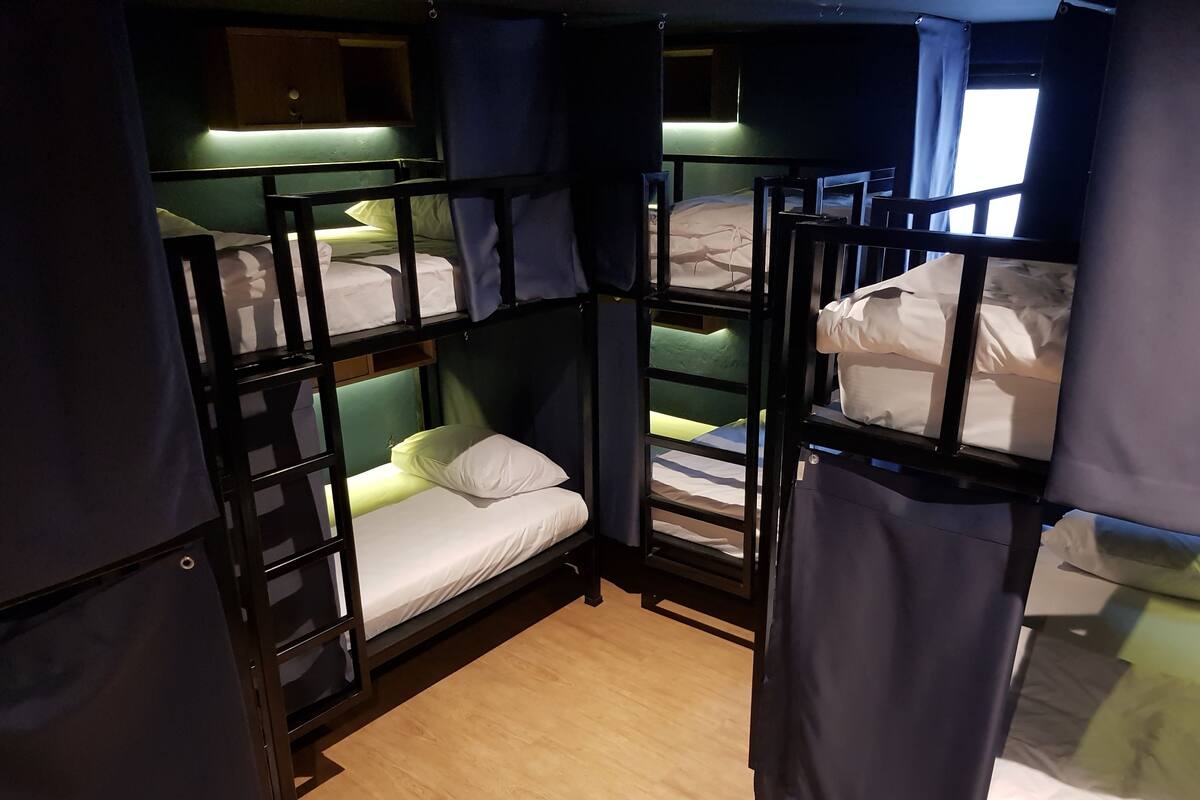 Habitación con literas de madera, suelo de madera y cortinas en las ventanas.