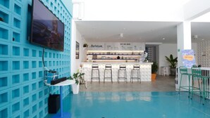 Zona de bar moderna con pared azul, televisor de pantalla plana y mostrador con taburetes.