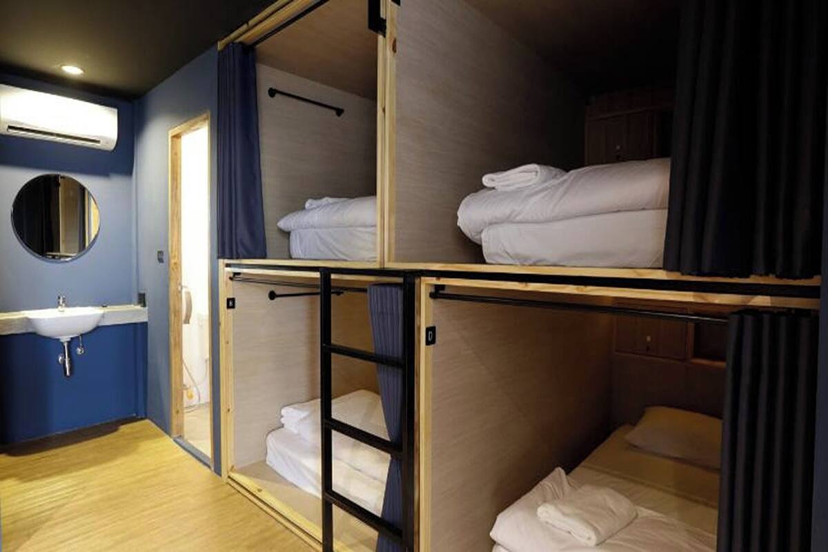 Un dormitorio con literas, un lavamanos, un espejo y una puerta.