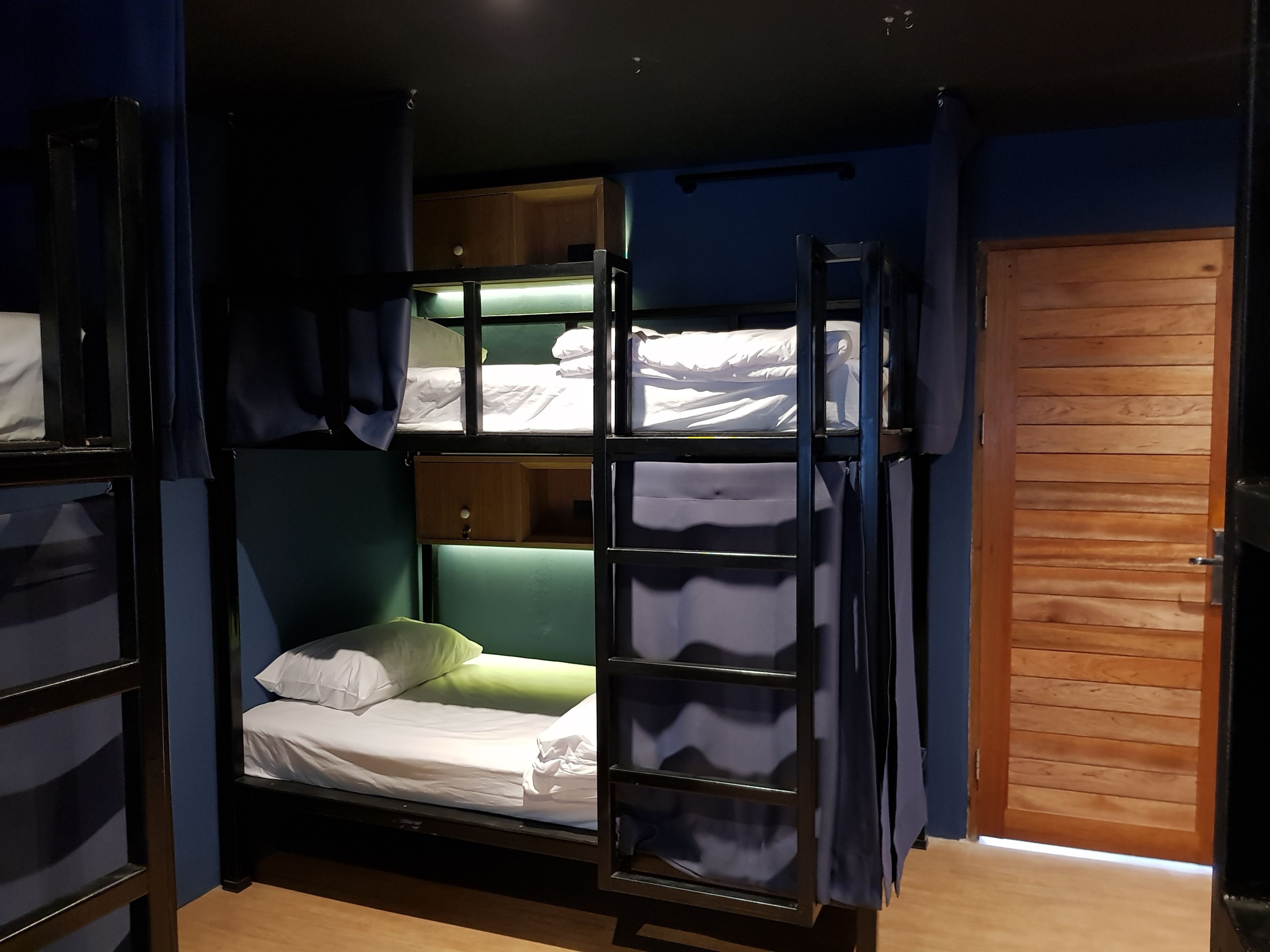 A bunk bed room with a wooden door and a small wooden cabinet.