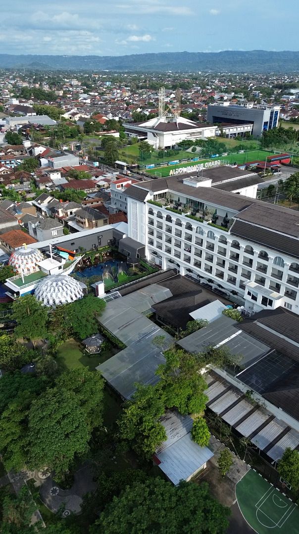 A large hotel with multiple floors, a swimming pool, and a tennis court.