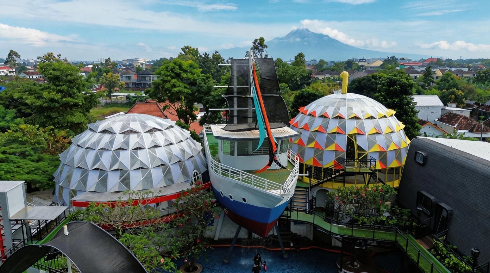 A water park with large geodesic domes, a boat ride, and a view of a mountain.