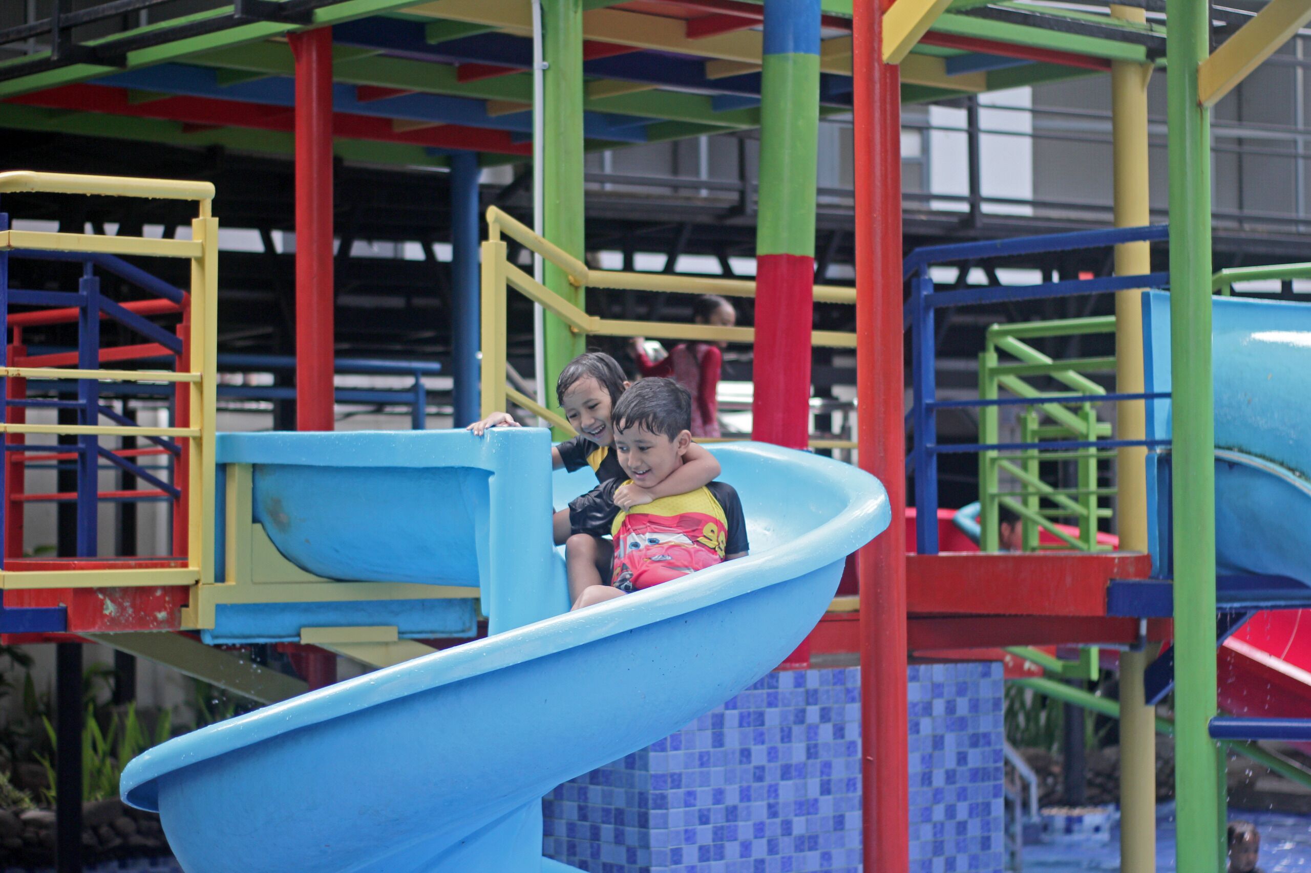 Un parque infantil con un tobogán azul y estructuras de juego coloridas.