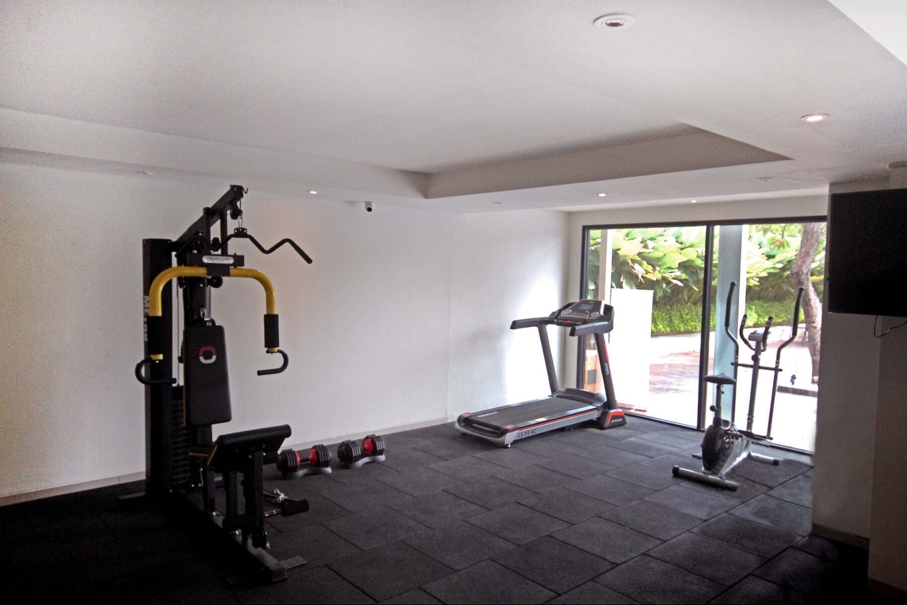 A gym with a treadmill, weight bench, and various exercise equipment.