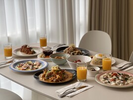 Una mesa de comedor con diferentes platos, entre ellos mariscos, arroz y postres, junto con vasos de jugo de naranja.