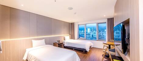 Una habitación de hotel moderna con dos camas, un televisor y vistas a la ciudad.
