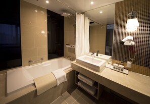 Enjoy a spacious bathroom with a large bathtub, dual sink vanity, and handheld showerhead.