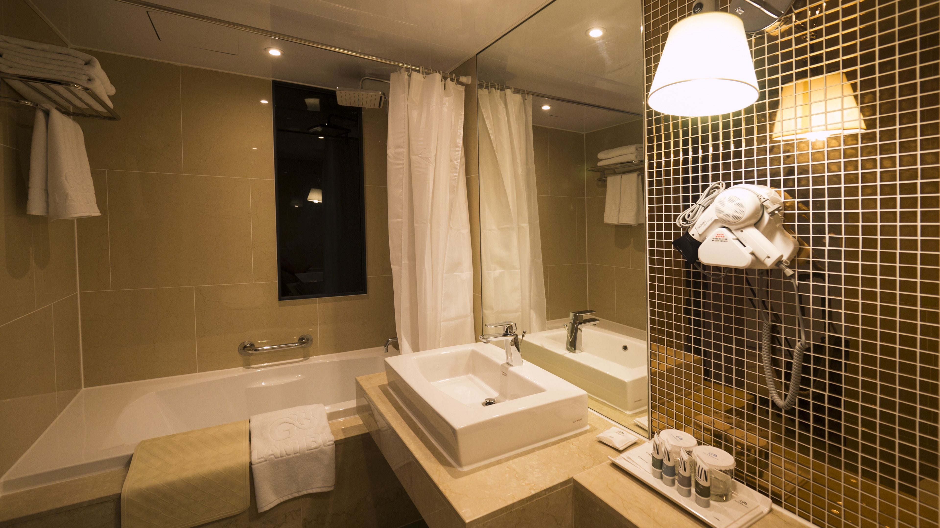 Une salle de bain moderne dotée d’une baignoire, d’une douche séparée et d’un meuble-lavabo avec un évier et un miroir.