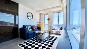A modern living room with a sofa, coffee table, and a patterned rug. - The First70 Hotel (Seogwipo)
