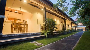A building with a covered porch, outdoor seating, and a cross on the wall.