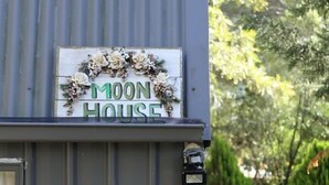 A building with a sign reading "Moon House" and a decorative wreath. - Moon House (Diamond Creek)